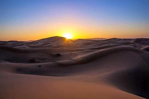 a sunset over the sand dunes in the desert at Desert Atmosphere M'Hamid in Mhamid