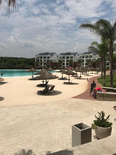 a resort with a beach with umbrellas and a pool at The Blyde Crystal Lagoon Cologne4 in Pretoria