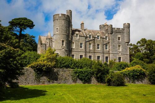 um velho castelo com uma parede de pedra e árvores em The Mournes view Farmhouse em Newcastle