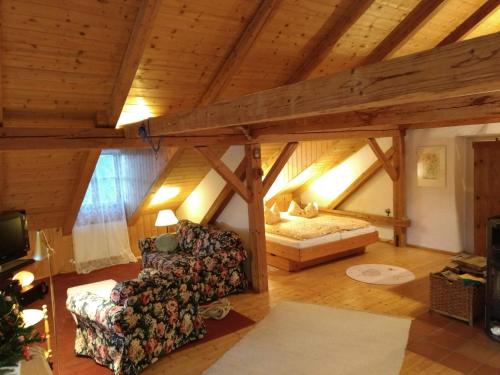een zolderkamer met een bank en een bed bij Ferienwohnung Lackenhäuser in Neureichenau