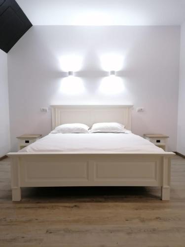a white bed in a white room with lights on it at Pensiunea Edelweiss in Voineasa