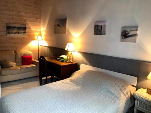 a bedroom with a bed and a desk and a couch at Les Nuits Bleues in Ars-en-Ré