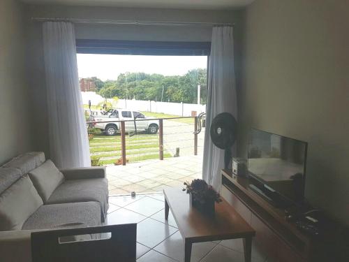 a living room with a couch and a large window at Condomínio Brisas do Amor in Pipa