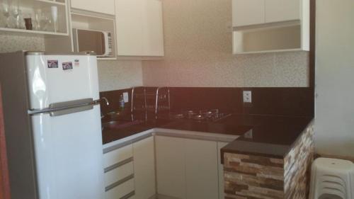 a kitchen with a white refrigerator and black counter tops at Condomínio Brisas do Amor in Pipa