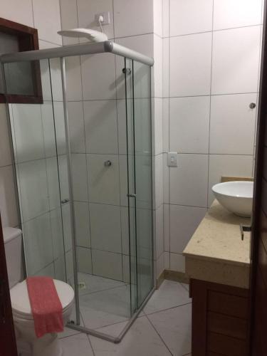een badkamer met een glazen douche, een toilet en een wastafel bij Condomínio Brisas do Amor in Pipa