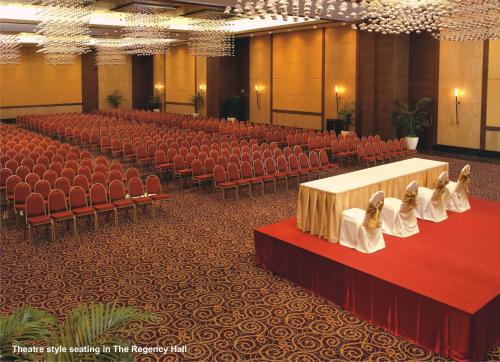 a large hall with red chairs and a table with bows at The Retreat Hotel & Convention Centre in Mumbai