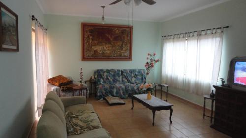 uma sala de estar com um sofá e uma televisão em Casa 200m da praia 3 dorm. p/ 12 pessoas em Peruíbe
