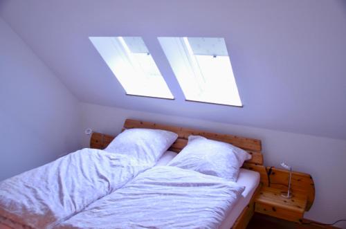 um quarto com uma cama com lençóis brancos e 2 janelas em Ferienwohnung Deichapfel im Alten Land (Jork) em Jork