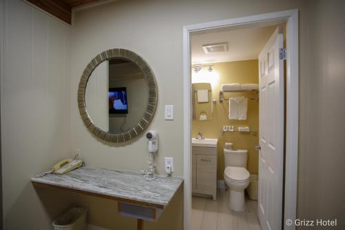 uma casa de banho com um lavatório, um espelho e um WC. em Grizz Hotel em Revelstoke