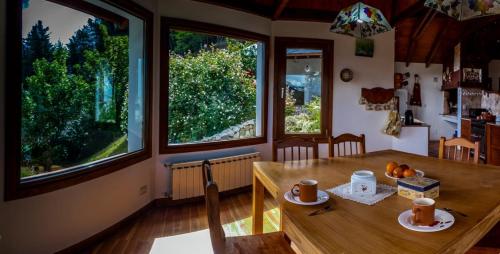 a dining room with a wooden table and two windows at Altos de Esquel in Esquel