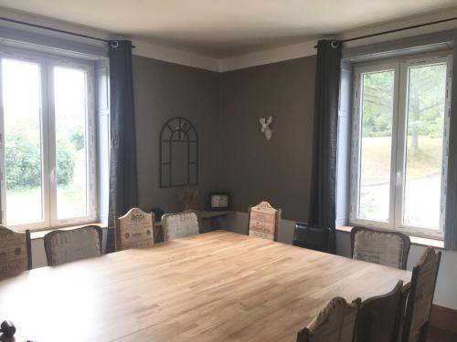 a large wooden table in a room with windows at Gîte Le 1902 in Brouvelieures