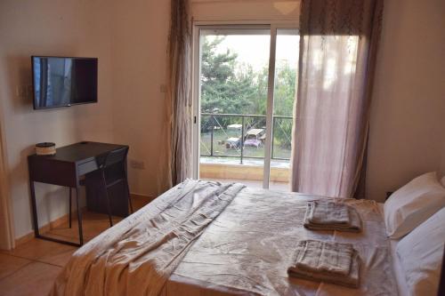 a bedroom with a bed and a window with a television at Raise Cosy Studio with pool in Limassol in Limassol