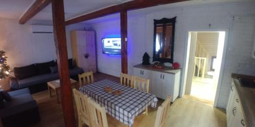 a kitchen and a living room with a table and chairs at Sielanówek - Orzechowa Chatka z sauną wanną termalną jacuzzi in Żywiec
