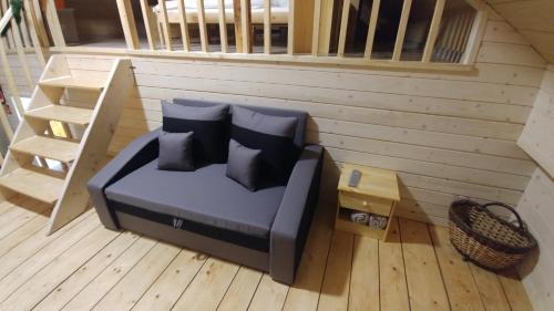 a couch with pillows sitting on a wooden floor at Sielanówek - Orzechowa Chatka z sauną wanną termalną jacuzzi in Żywiec