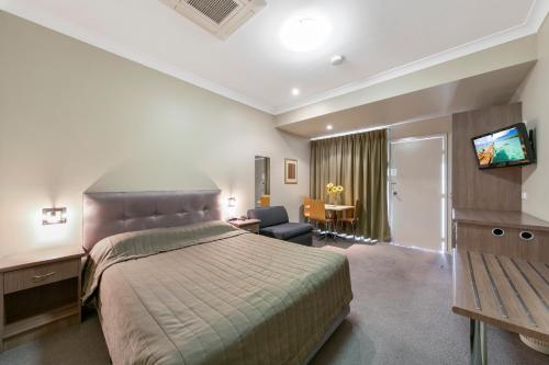 a hotel room with a bed and a desk at Cessnock Motel in Cessnock