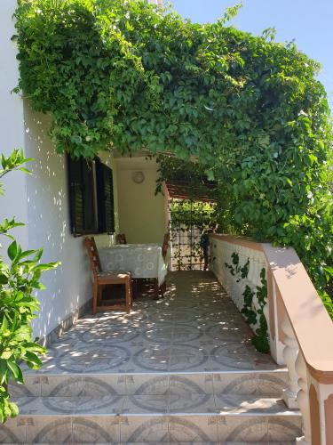 a patio with an arch with a table and a chair at Apartments Elena in Ugljan