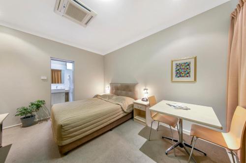 セスノックにあるCessnock Motelのベッドとテーブルのある小さな寝室