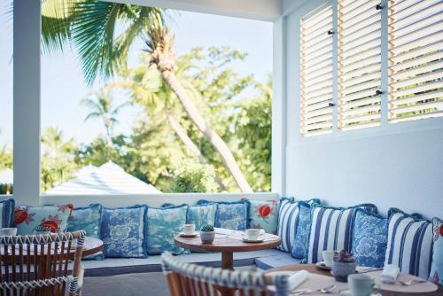 a patio with a blue couch and tables and a palm tree at La Samanna, A Belmond Hotel, St Martin in Baie Longue