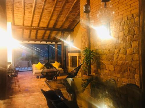 a living room with a stone wall and a table and chairs at Hotel Casas de Campo El Ciruelo in San Gil
