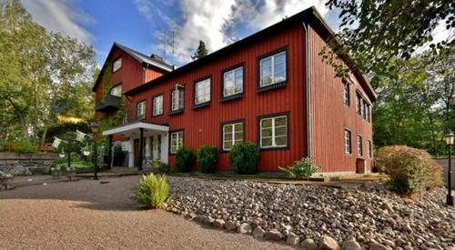 a red house with a gravel driveway in front of it at Fågelfors Wärdshus in Fågelfors