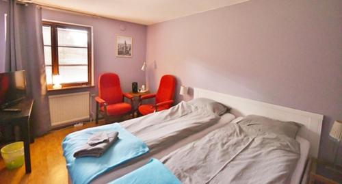 ein Schlafzimmer mit einem Bett und zwei roten Stühlen in der Unterkunft Fågelfors Wärdshus in Fågelfors