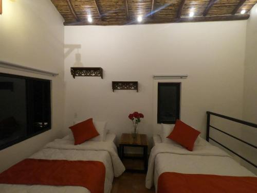 a room with two beds and a vase of flowers at Hotel Casas de Campo El Ciruelo in San Gil