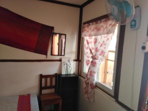 a bedroom with a window with a curtain and a chair at Mama Hostel & Guest House in El Nido