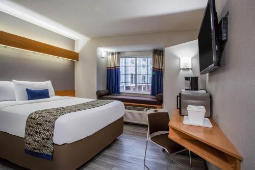 um quarto de hotel com uma cama grande e uma janela em Microtel Inn & Suites by Wyndham Southern Pines Pinehurst em Southern Pines