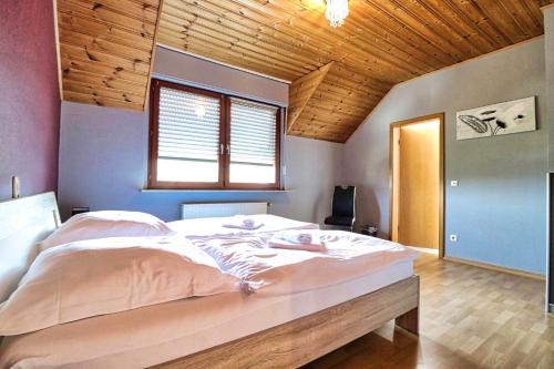 a large bed in a bedroom with a wooden ceiling at obermaubach-am see Apartments in Kreuzau