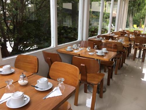 un restaurant avec des tables et des chaises en bois et des fenêtres dans l'établissement Hotel El Faro, à Villa Gesell