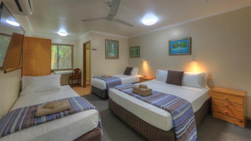 a hotel room with two beds and a desk at Atherton Hinterland Motel in Atherton