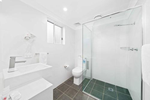 uma casa de banho com um WC, um lavatório e um chuveiro em WM Bankstown em Bankstown