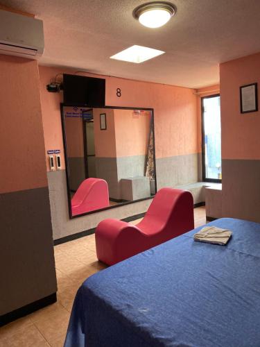 - une salle d'attente avec des chaises rouges et un miroir dans l'établissement Motel Flamingos, à Oaxaca