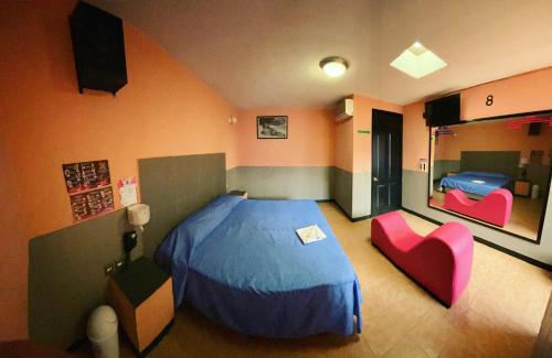 a bedroom with a blue bed and two pink chairs at Motel Flamingos in Oaxaca City