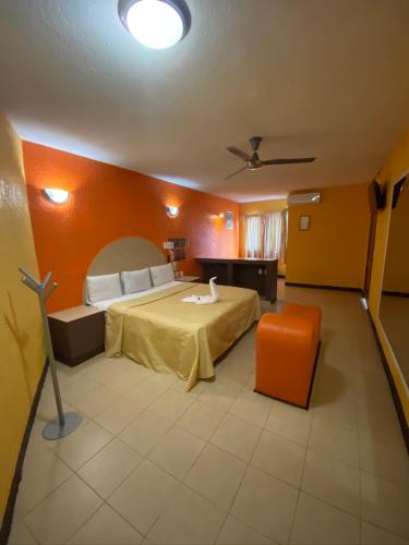 - une chambre avec un lit et un mur orange dans l'établissement Auto Hotel Villaferr, à Oaxaca