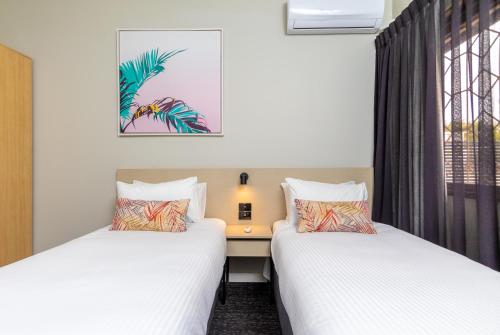 two beds in a room with a desk and a window at Nightcap at Springwood Hotel in Springwood