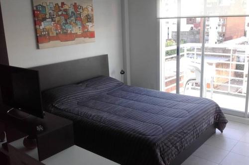 a bedroom with a bed with a blue blanket and a window at Departamento confortable en Congreso in Buenos Aires