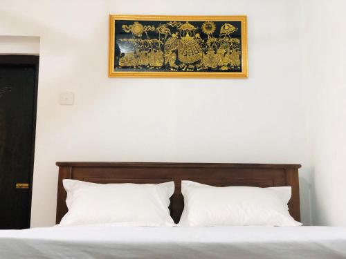a picture hanging above a bed with white pillows at VILLA 826 Ahungalla in Ahungalla