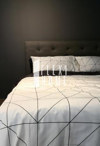 a bed with a white comforter with the word home written on it at NETFLIX-Pinnacle PJ, Fantastic City View, 1-6 Guests Designed Duplex Home by Flexihome-MY in Petaling Jaya
