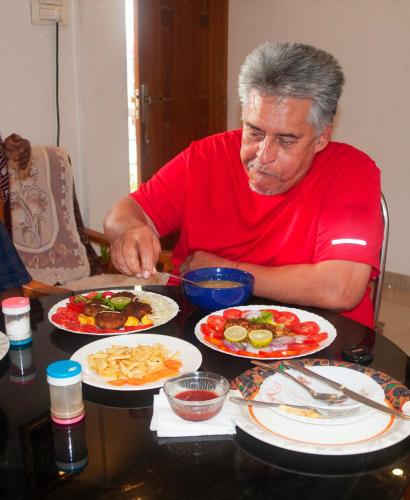 a man sitting at a table with plates of food at Heather Home Stay in Cochin