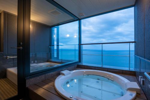 a large bathroom with a tub and a large window at AMANE resort GAHAMA in Beppu