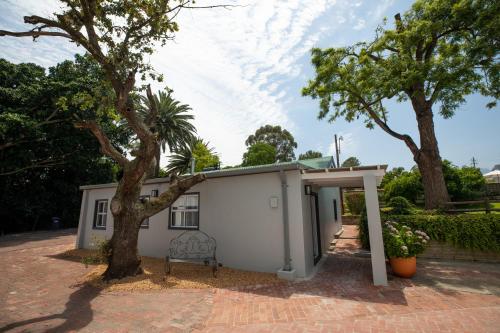 a small white shed with a tree in front of it at Sweetwater Guesthouse in Wellington