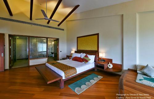 a bedroom with a large bed with a ceiling fan at Gulmohar Greens Golf & Country Club in Sānand