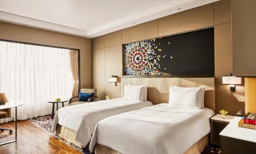 two beds in a hotel room with a painting on the wall at Taj Agra in Agra
