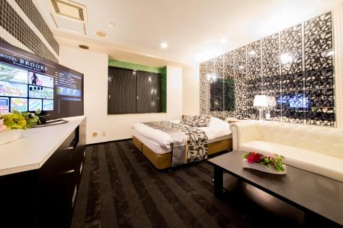 a hotel room with a bed and a couch and a tv at Hotel Brooks (Adult Only ) in Kasukabe