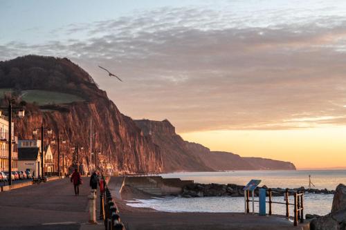 a group of people walking along a beach with a mountain at The Elizabeth in Sidmouth