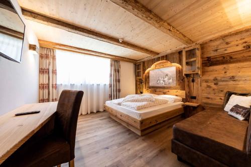 a bedroom with a bed and a desk at Garni Hotel Residence Diamant in San Vigilio Di Marebbe