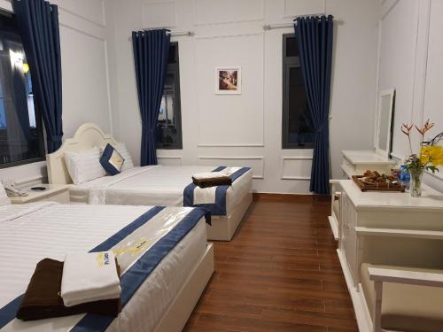 2 letti in una camera con tende blu di Coco Village Phu Quoc Resort & Spa a Phu Quoc