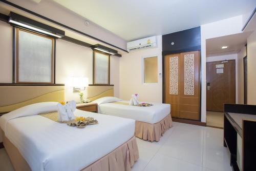 a hotel room with two beds and a television at Asia Cha-am Hotel in Cha Am