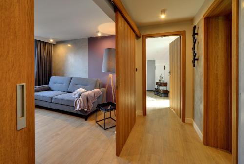 a living room with a blue couch and a hallway at Walizka Wspomnień in Karpacz